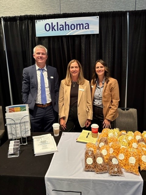 Travis Colt, Leah Keele, and Jordan Ensley standing behind their booth at the WCI.